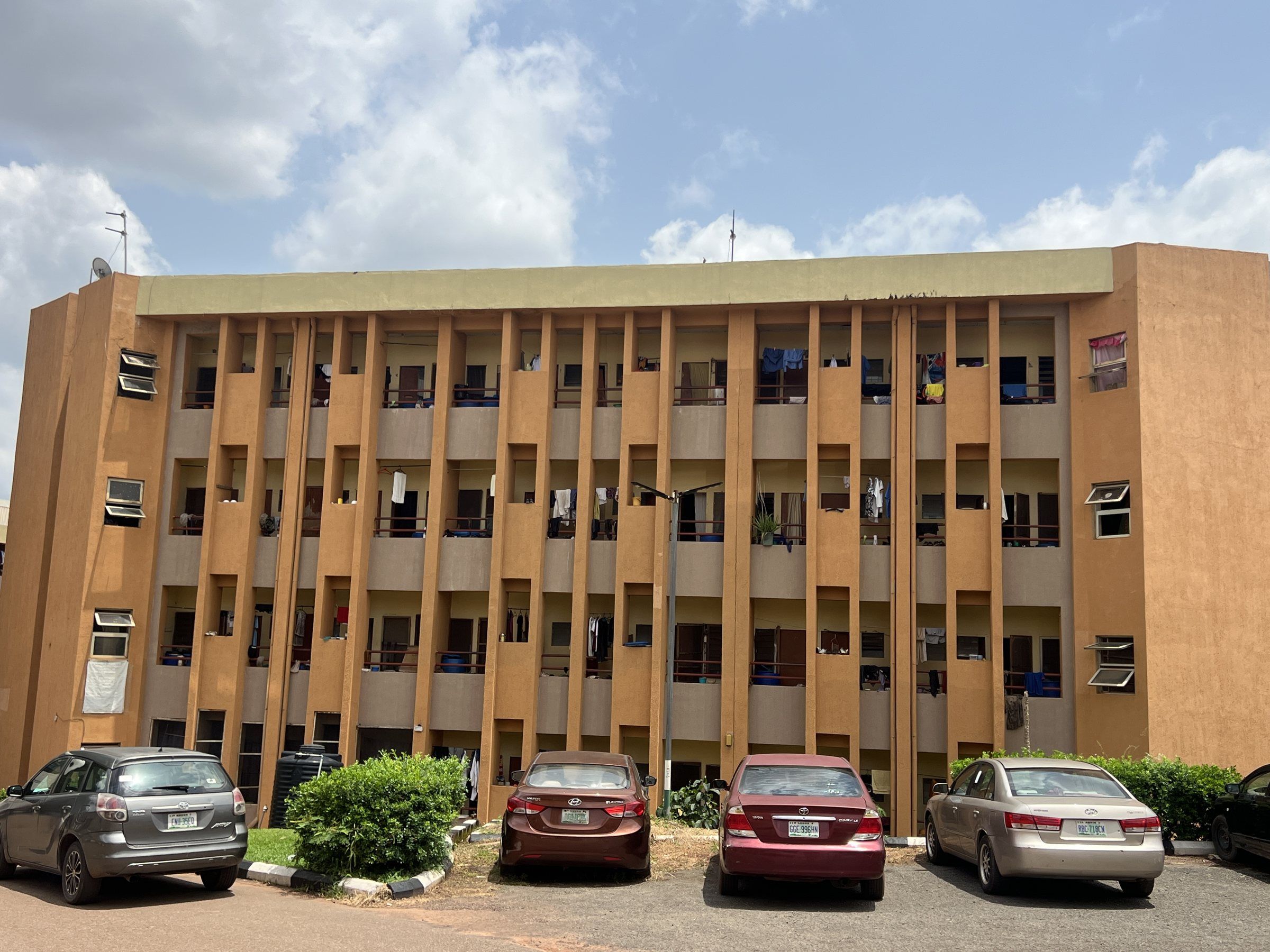 A four-storey student hostel with cars parked in front.