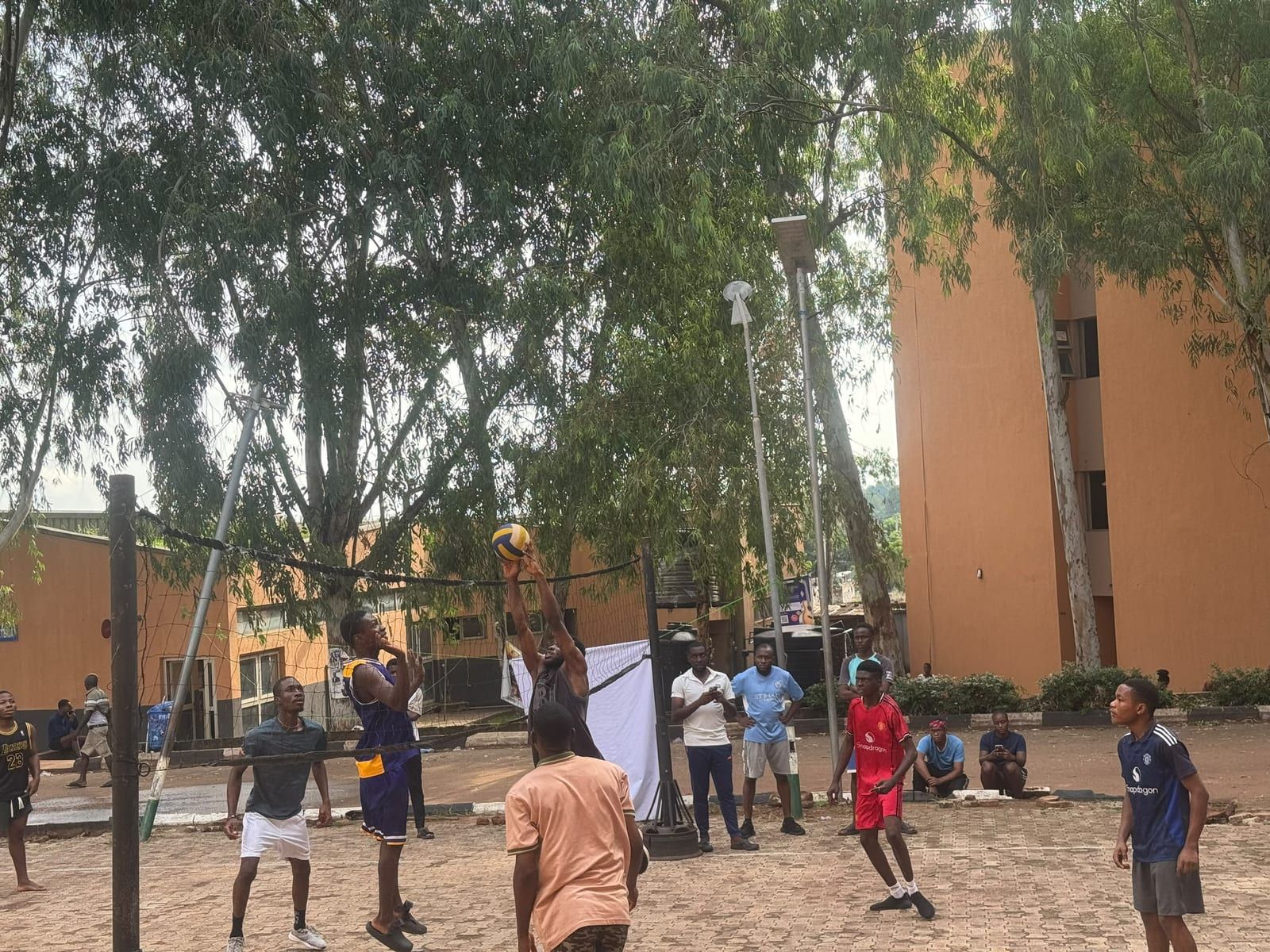 Students playing on an outdoor court beside a college building.