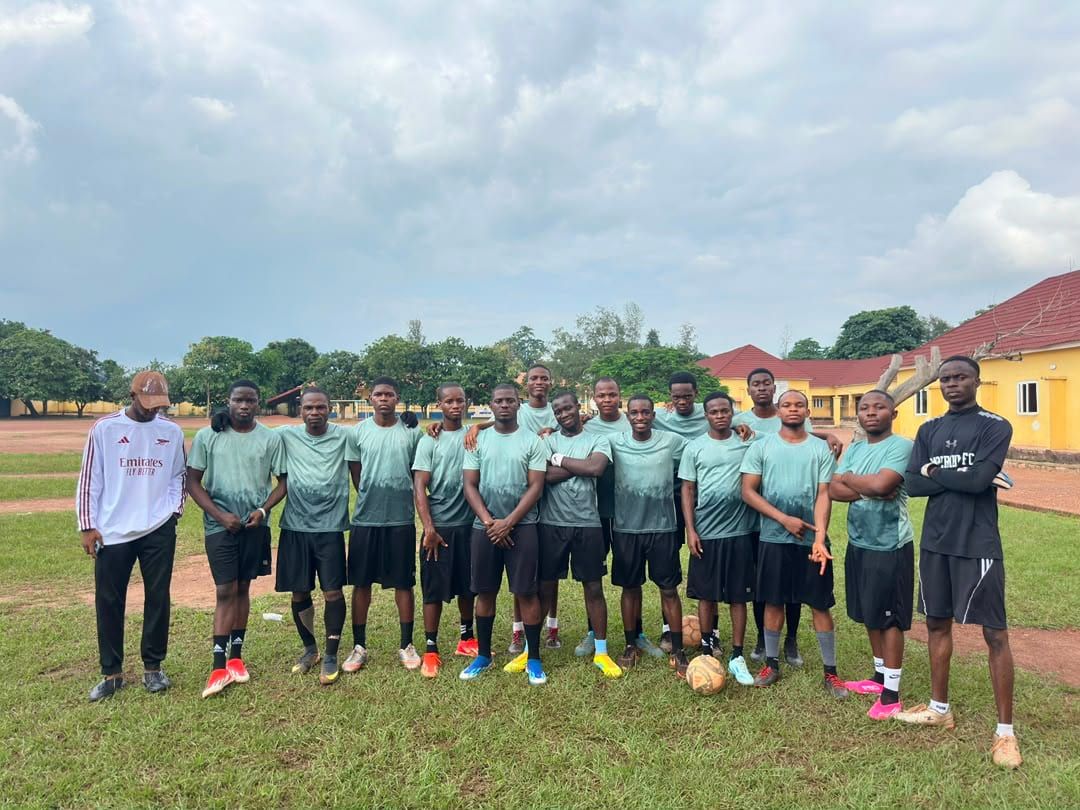 The ESUMSA football team in a line on a grass pitch with their coach.
